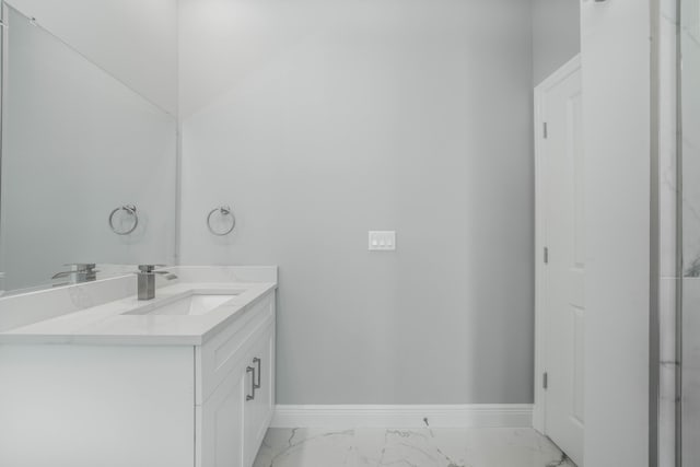 bathroom with marble finish floor, vanity, and baseboards