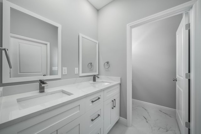 full bathroom with double vanity, marble finish floor, baseboards, and a sink