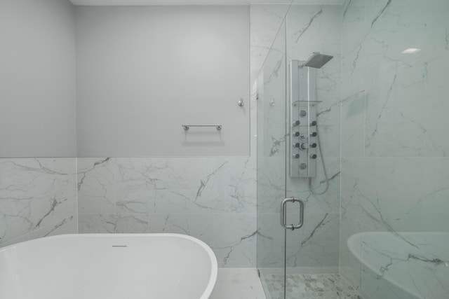 full bathroom featuring a marble finish shower, a soaking tub, and tile walls