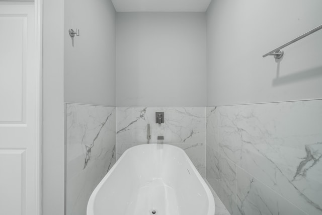 bathroom featuring a wainscoted wall and a freestanding bath