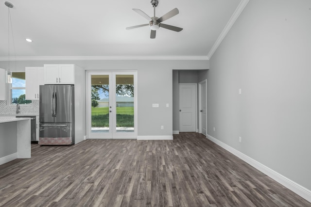 unfurnished living room featuring dark wood finished floors, baseboards, a wealth of natural light, and ornamental molding