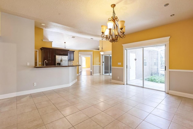 interior space featuring a notable chandelier, light tile patterned floors, baseboards, and a textured ceiling