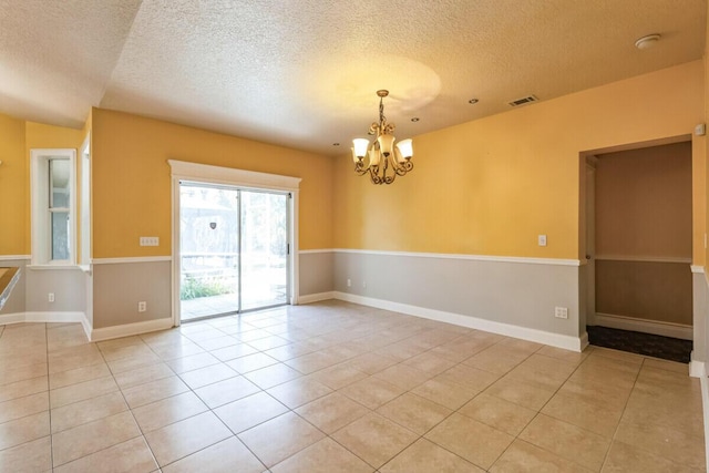 spare room featuring light tile patterned floors, a notable chandelier, and a textured ceiling