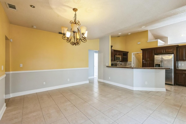 spare room featuring light tile patterned floors, visible vents, a sink, vaulted ceiling, and a notable chandelier