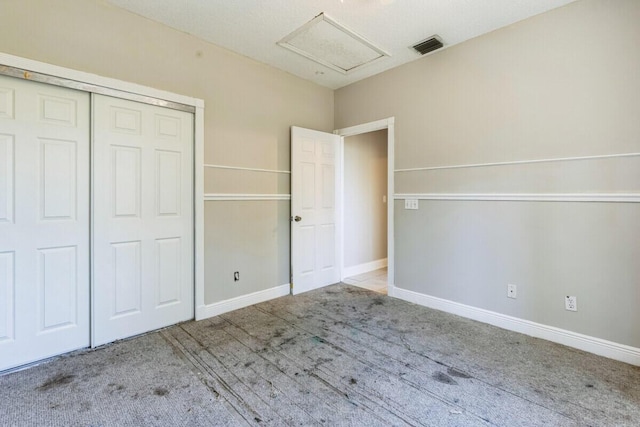 unfurnished bedroom with visible vents, a closet, carpet flooring, baseboards, and attic access