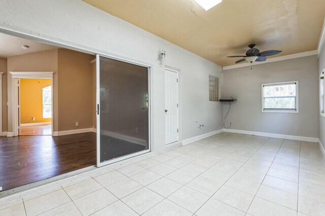 empty room with tile patterned flooring, baseboards, and ceiling fan