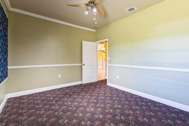 empty room with baseboards, visible vents, carpet floors, ceiling fan, and crown molding