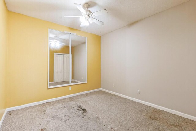 spare room featuring carpet flooring, baseboards, and ceiling fan