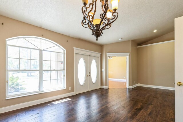 foyer entrance with french doors, dark wood-type flooring, a chandelier, and vaulted ceiling