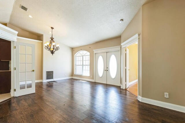 foyer entrance featuring visible vents, vaulted ceiling, french doors, dark wood-style floors, and a notable chandelier