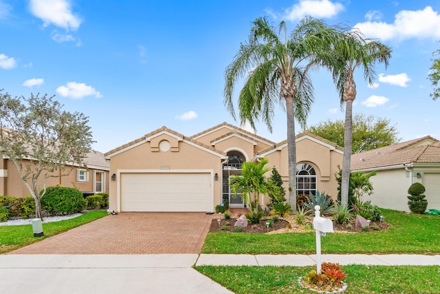 view of front of home featuring stucco siding, a front lawn, decorative driveway, an attached garage, and a tiled roof