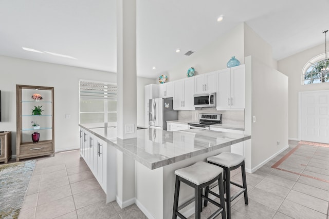 kitchen featuring light tile patterned floors, white cabinetry, stainless steel appliances, and a kitchen breakfast bar