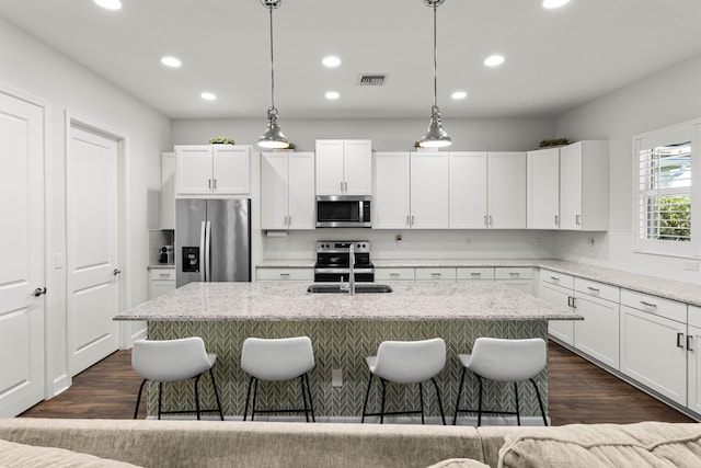 kitchen with visible vents, a kitchen bar, dark wood-type flooring, a sink, and appliances with stainless steel finishes