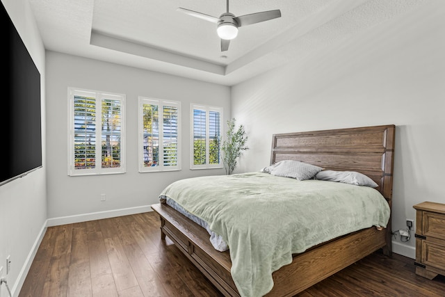 bedroom featuring a tray ceiling, baseboards, and hardwood / wood-style floors