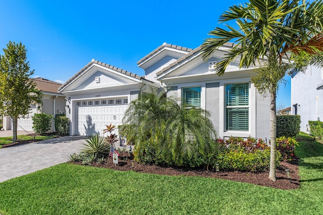 view of front of house with decorative driveway, stucco siding, an attached garage, and a tile roof