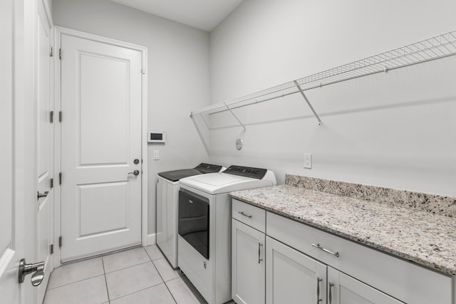 clothes washing area with light tile patterned floors, cabinet space, and independent washer and dryer