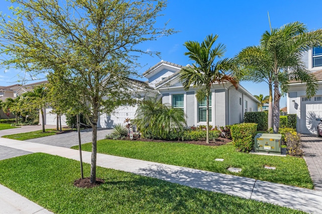 view of front of home featuring a garage, stucco siding, decorative driveway, and a front lawn