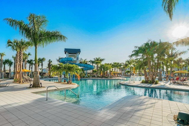 community pool with a patio area and a water slide