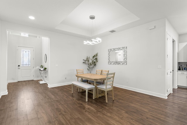 dining area with dark wood finished floors, visible vents, baseboards, and a tray ceiling