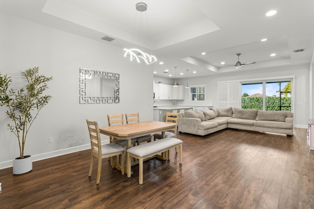 dining room featuring a raised ceiling, dark wood-style floors, baseboards, and visible vents