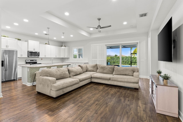 living area with dark wood-style floors, visible vents, recessed lighting, and a raised ceiling