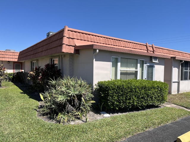 view of side of home with a yard, mansard roof, and a tile roof