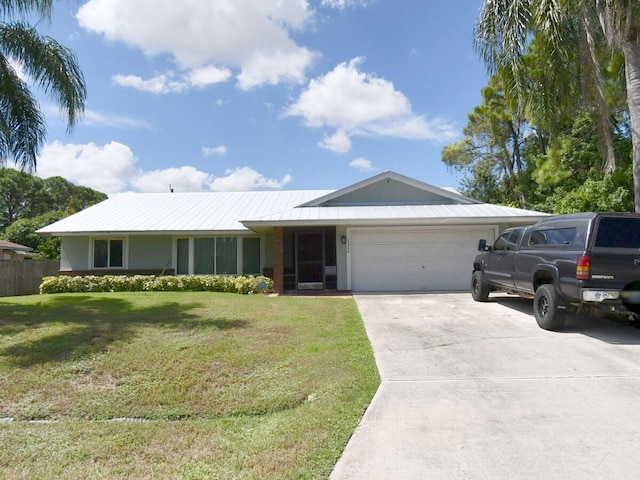 ranch-style home with a front yard, concrete driveway, an attached garage, and metal roof