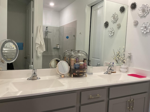 bathroom featuring double vanity, a stall shower, and a sink