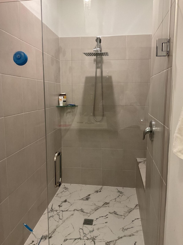 full bath with a shower stall and marble finish floor