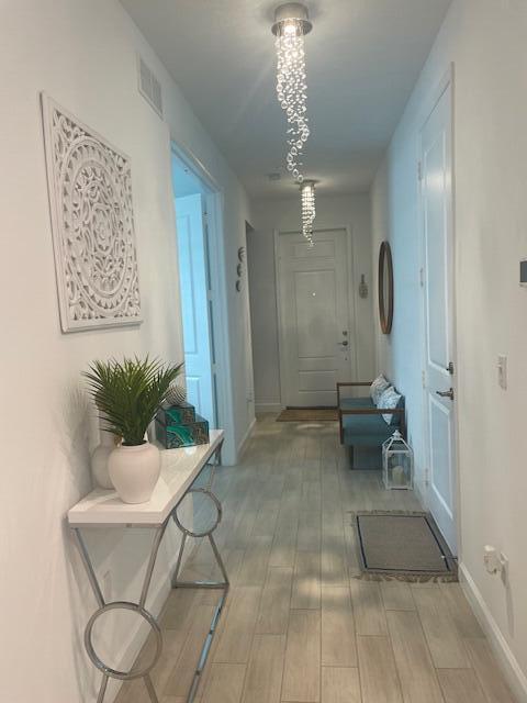 corridor featuring wood finish floors, visible vents, and baseboards