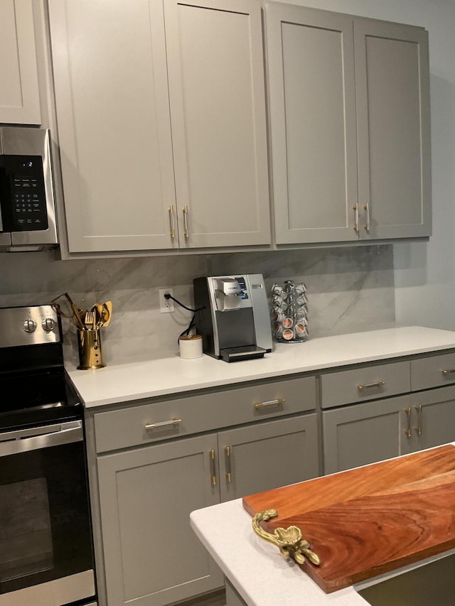 kitchen with decorative backsplash, appliances with stainless steel finishes, and gray cabinetry