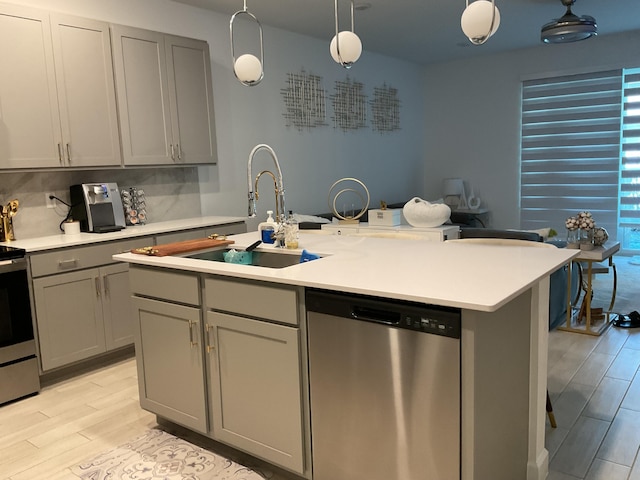 kitchen with wood finish floors, light countertops, gray cabinets, stainless steel appliances, and a sink