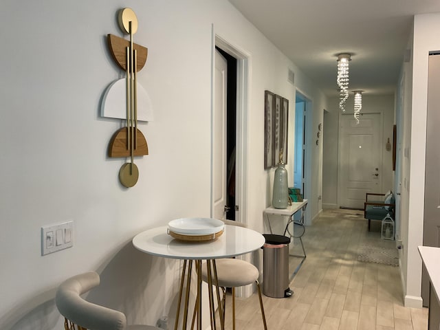 hallway featuring light wood finished floors, visible vents, and baseboards