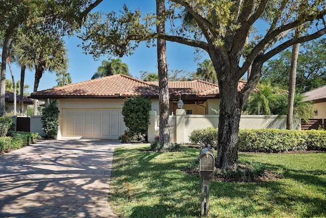 mediterranean / spanish home featuring a front yard, fence, driveway, a garage, and a tiled roof