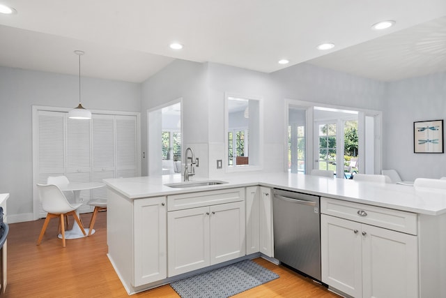 kitchen with a sink, stainless steel dishwasher, a peninsula, and light countertops