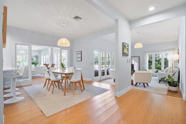 dining area with light wood finished floors, visible vents, a healthy amount of sunlight, and baseboards