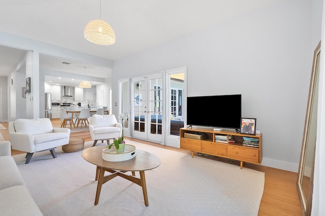 living area featuring french doors, baseboards, and light wood-style flooring