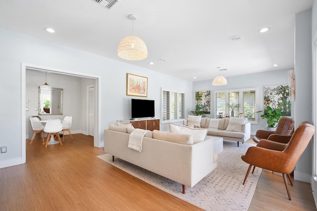 living room featuring recessed lighting, plenty of natural light, visible vents, and light wood-type flooring