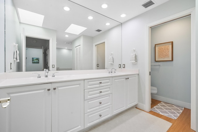 bathroom featuring wood finished floors, visible vents, recessed lighting, a sink, and toilet