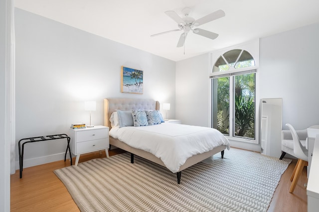 bedroom with light wood finished floors, a ceiling fan, and baseboards