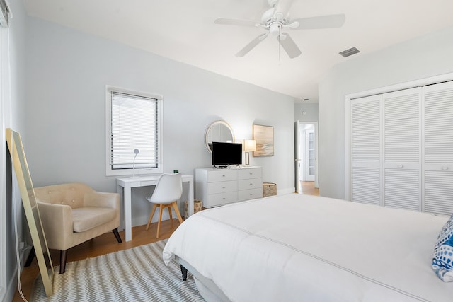 bedroom featuring ceiling fan, visible vents, a closet, and wood finished floors