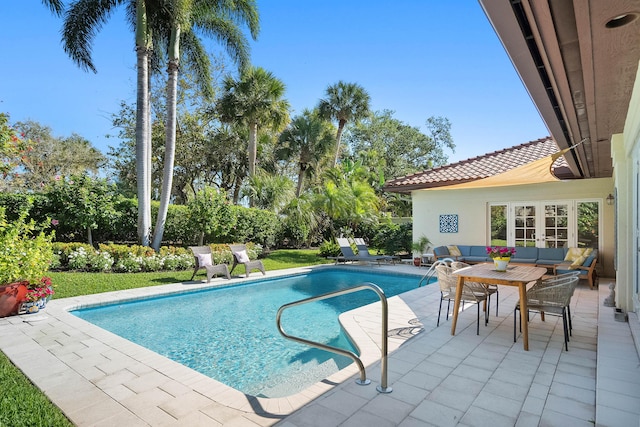 outdoor pool with a patio area, a lawn, french doors, and an outdoor hangout area