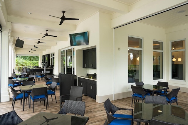 view of patio featuring ceiling fan, a deck, outdoor dining space, and a sink