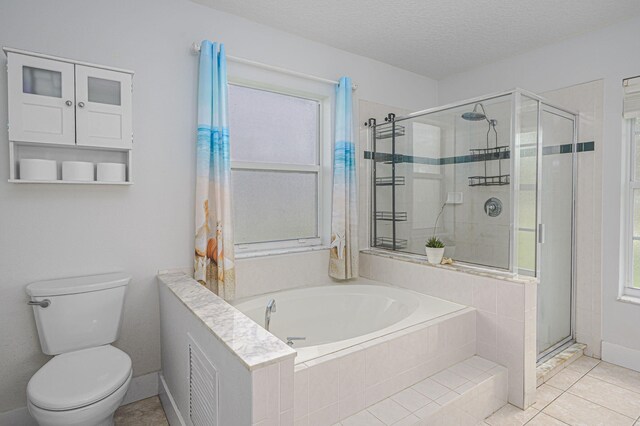 full bathroom featuring a shower stall, a textured ceiling, a garden tub, toilet, and tile patterned floors