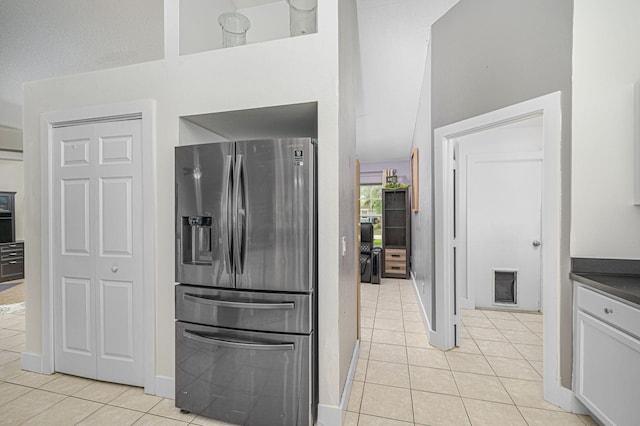 kitchen with light tile patterned flooring, white cabinetry, dark countertops, and stainless steel fridge with ice dispenser