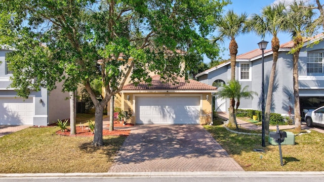 view of front of home with stucco siding, decorative driveway, a garage, and a tiled roof