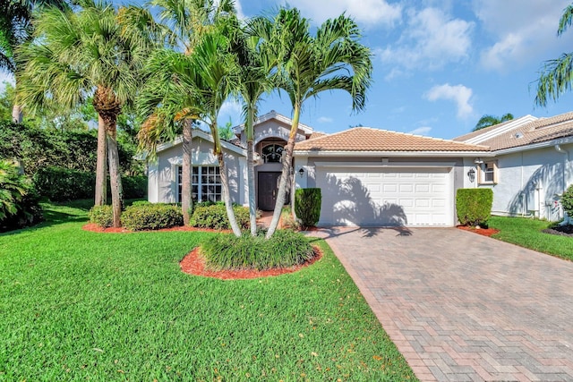 view of front facade featuring stucco siding, a tile roof, decorative driveway, a front yard, and an attached garage