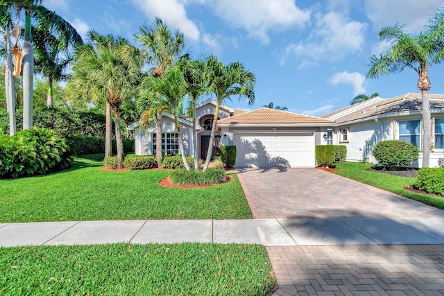 view of front of property featuring stucco siding, decorative driveway, a front yard, a garage, and a tiled roof