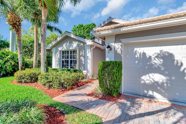 exterior space with a tiled roof, an attached garage, and stucco siding