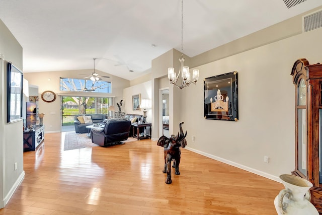 living room featuring visible vents, light wood-style flooring, ceiling fan with notable chandelier, baseboards, and vaulted ceiling